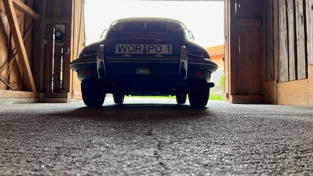 Porsche 356 Super 90 in Rückansicht am Ausgang einer Scheune während der Symphonieporsche Dreharbeiten
